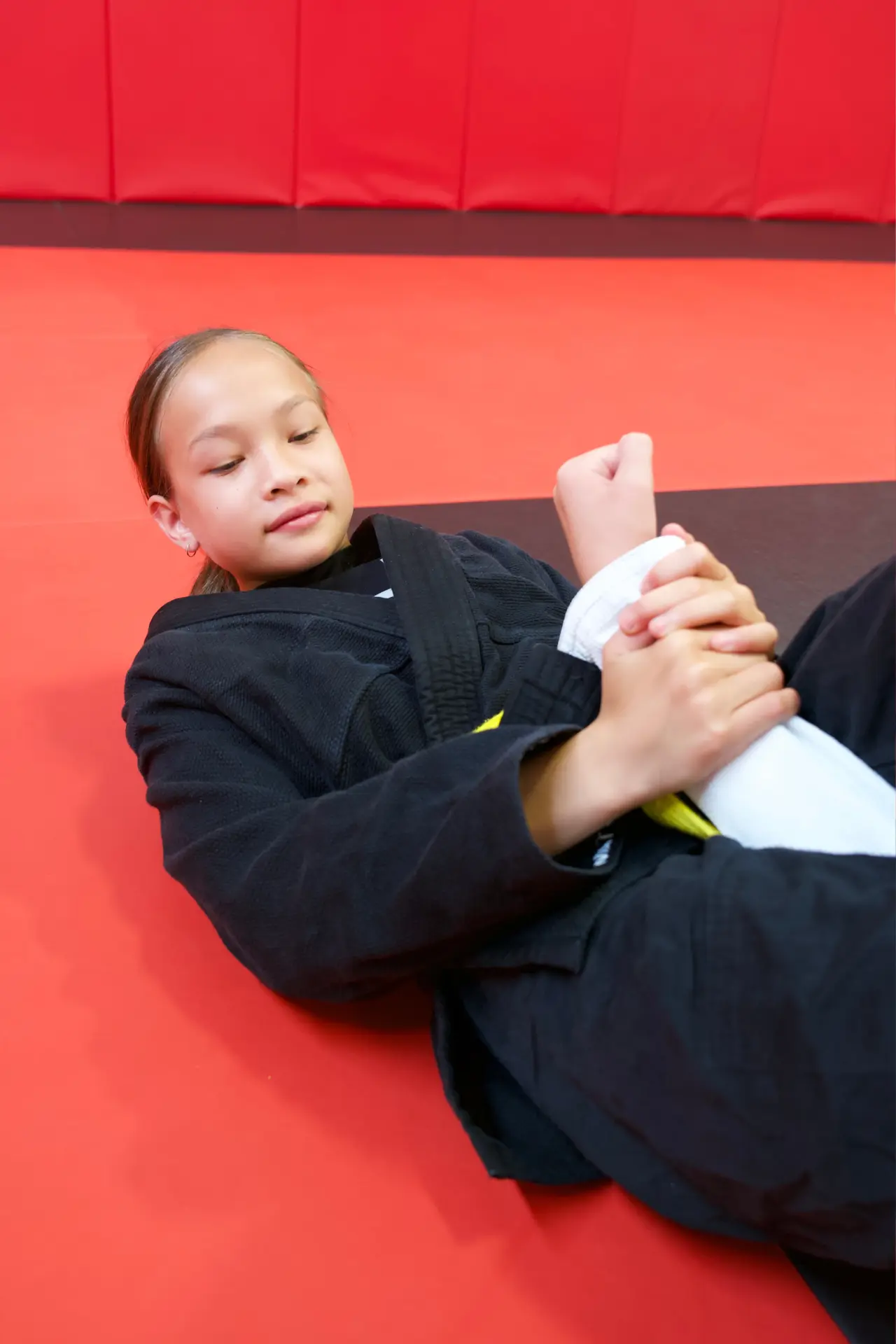 Close-up of a student on their back working an armbar grip detail during Brazilian Jiu Jitsu practice