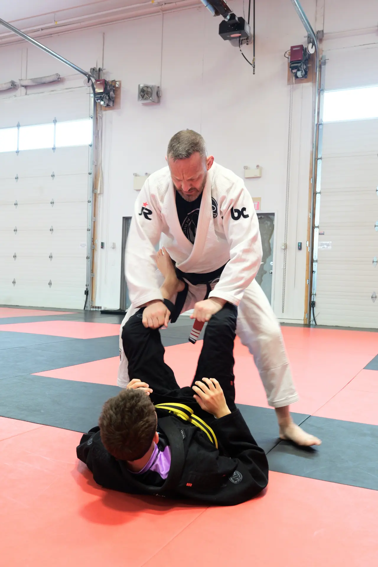 Instructor passing a student's guard during a Brazilian Jiu Jitsu class at Arashi-Do Red Deer